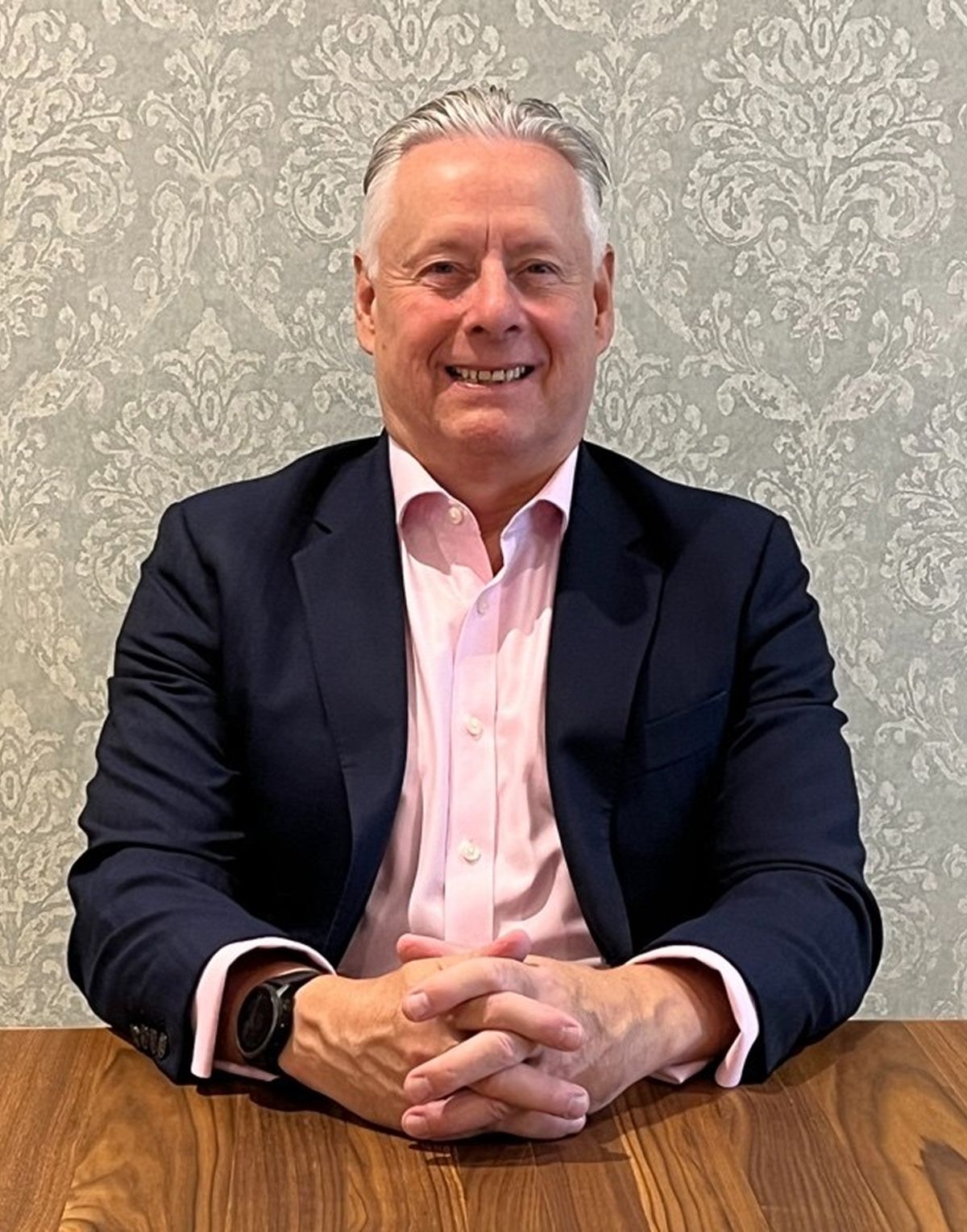 Neil Burns, seated at a table and smiling